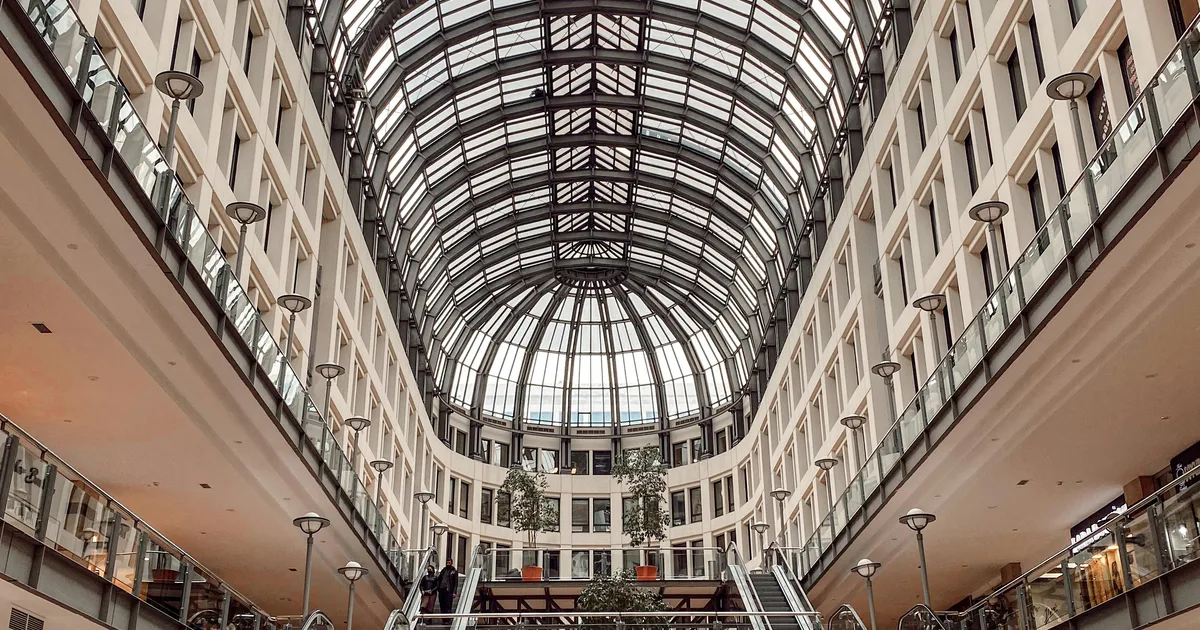 Atrio de un centro comercial con accesos, escaleras y zonas de circulacion.