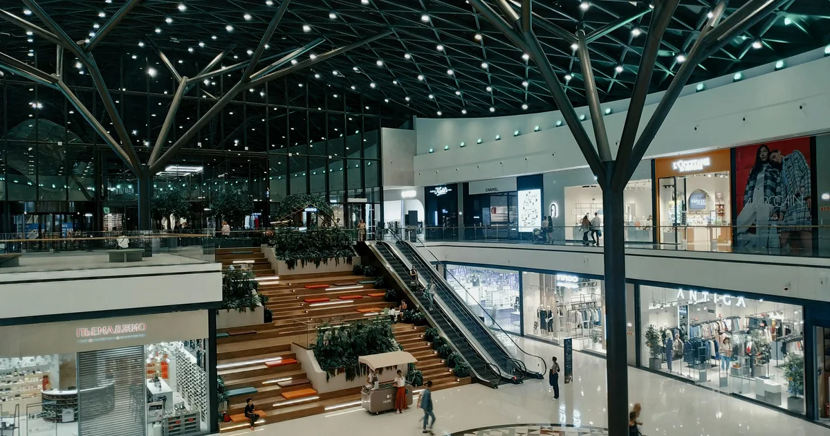 Atrio moderno de un centro comercial con tiendas y zonas de paso.